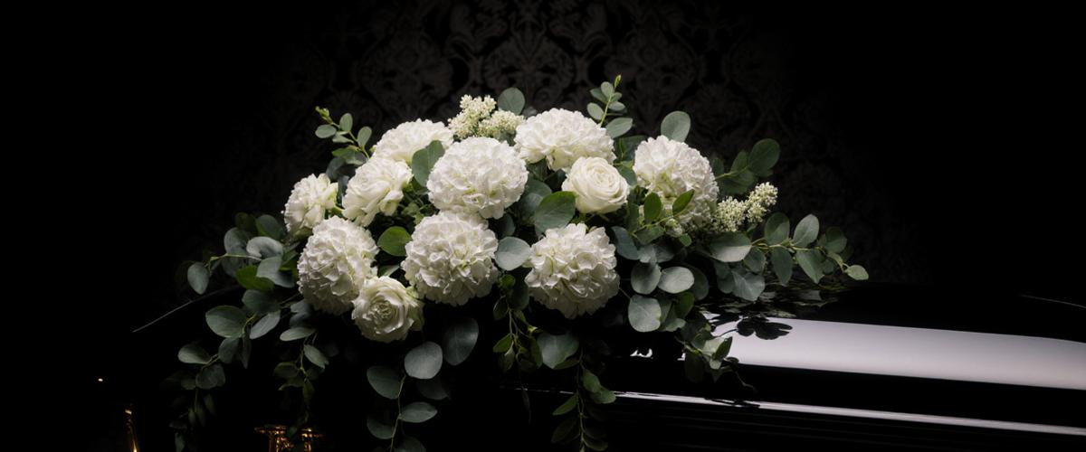 Elegant white and green casket spray with seasonal blooms